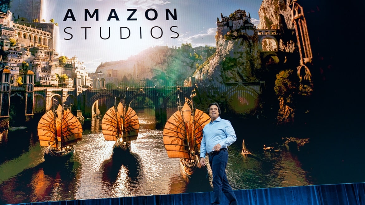 Eric Iverson of Amazon Studios in front of a scenic image from The Lord of the Rings: Rings of Power