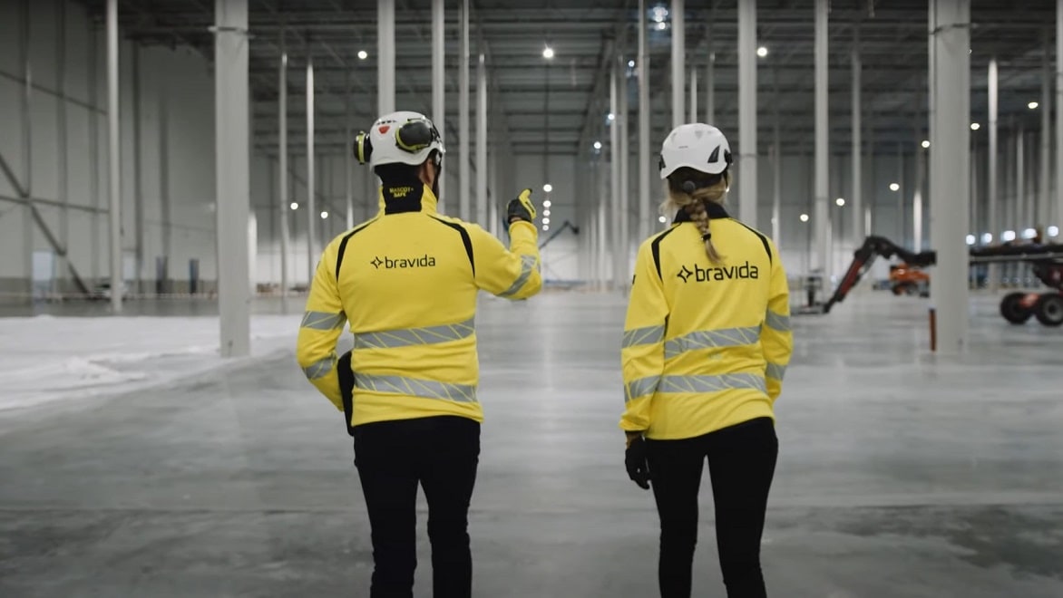 Two Bravida workers walk through a cavernous construction site