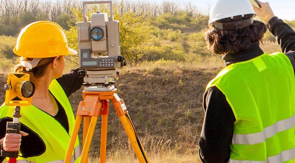 两名工程师使用他们的设备在工地上测量土地。