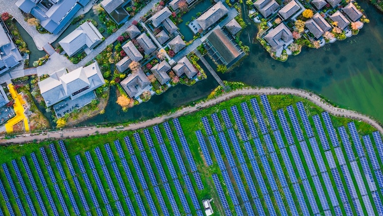 An aerial view of buildings next to a field of solar panels.