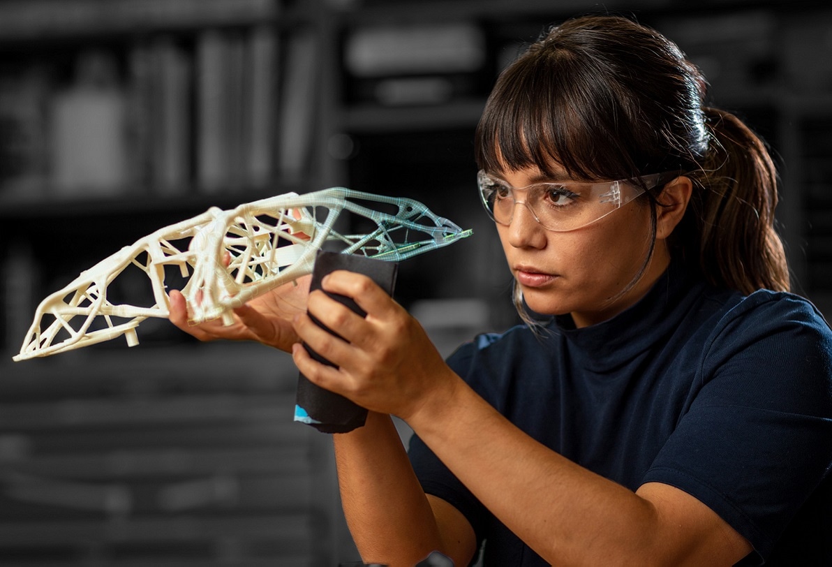 A woman examines a 3D printed object.