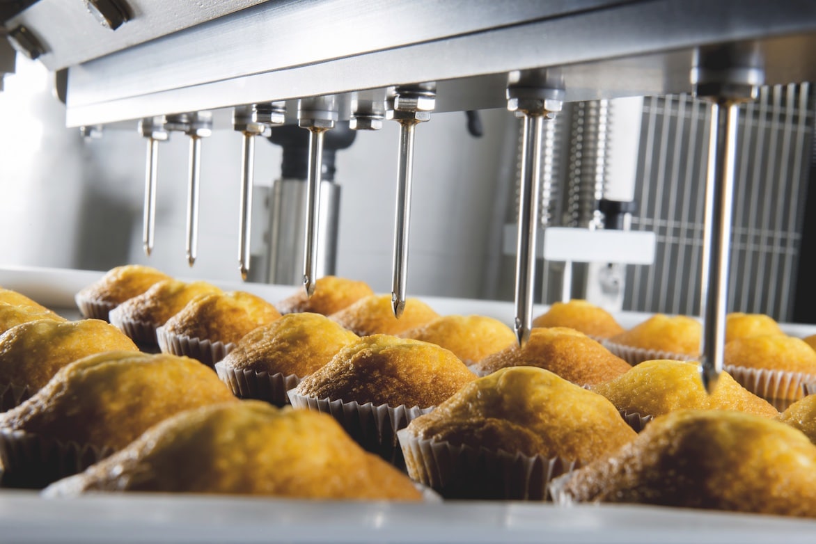 Cupcake injector equipment on a production line with cupcakes below