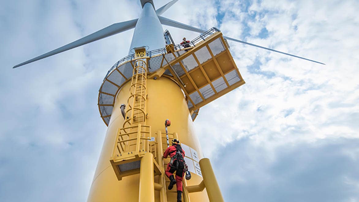 Engineers climb a wind turbine at an offshore wind farm.