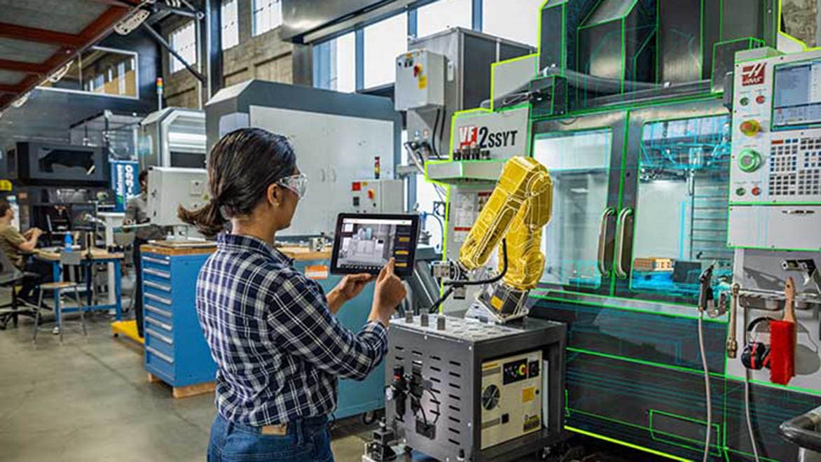 ロボットアームの前でタブレットを手にする女性。