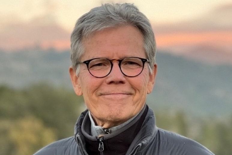 Headshot of BamCore CEO Hal Hinkle—smiling, wearing glasses, blurred background of mountain sunset view.
