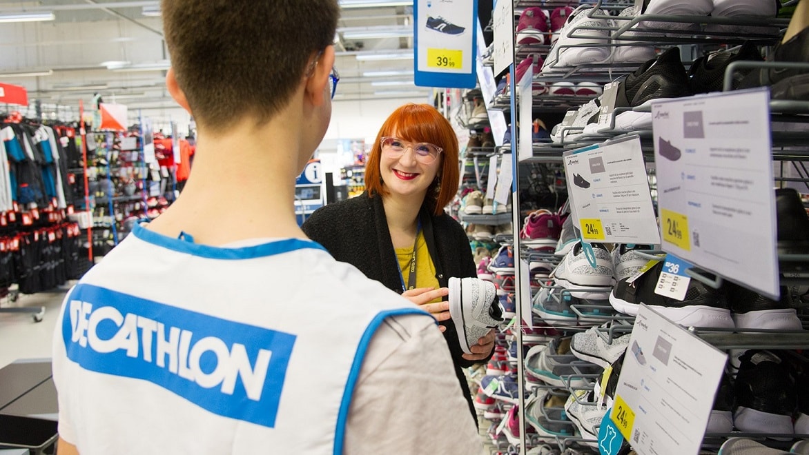 Alkalmazottak tanulmányoznak egy cipőállványt az egyik Decathlon-áruházban.