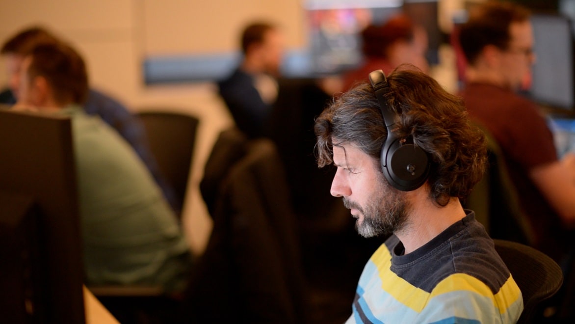 Twórca ze słuchawkami na uszach koncentrujący się na ekranie komputera w studiu Jellyfish Pictures.