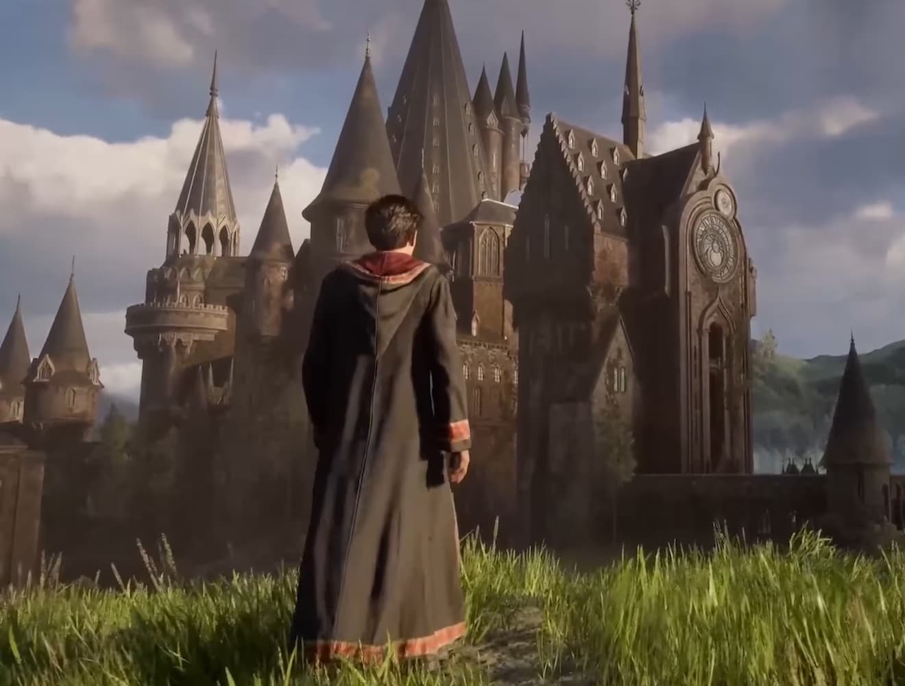 A character in a wizard’s robe walks towards a large gothic building in a still from the Hogwarts Legacy video game.