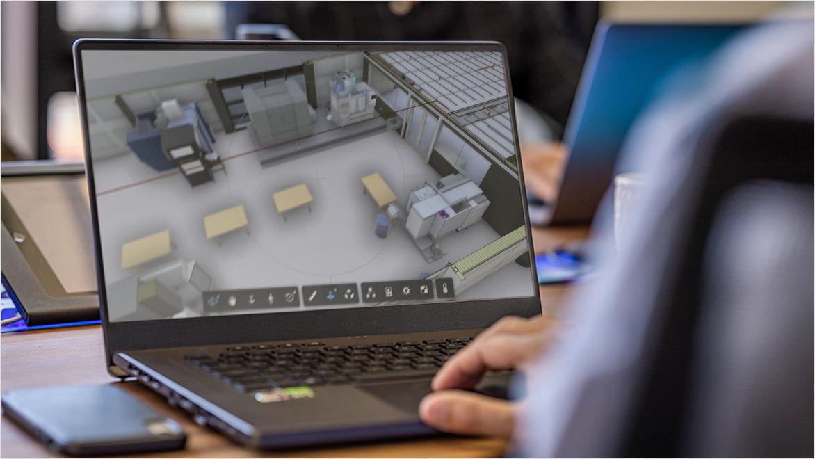 An over-the-shoulder view shows a person using Autodesk space design software on a laptop.