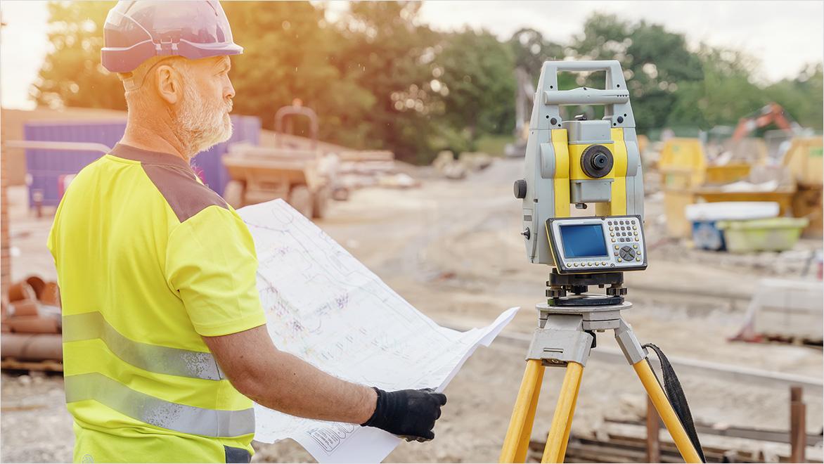 A construction worker takes survey measurements onsite with a digital scanner.