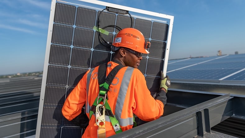A construction worker prepares a solar panel for installation.