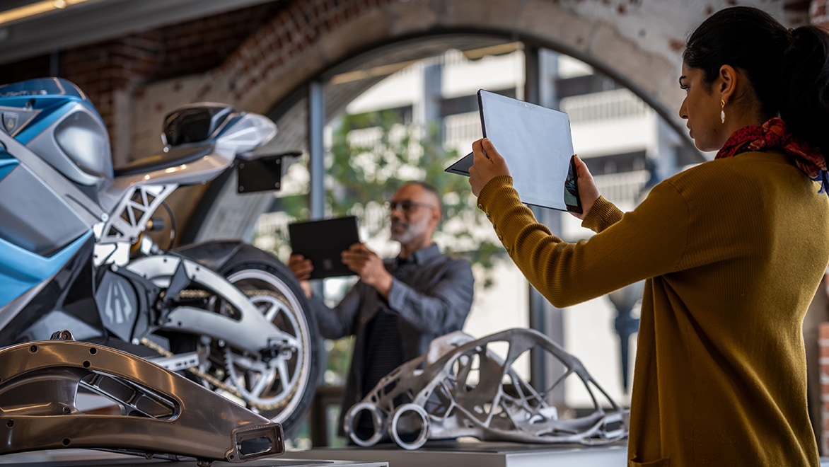 A woman views an iPad showing enhanced views of a motorcycle prototype using augmented reality.