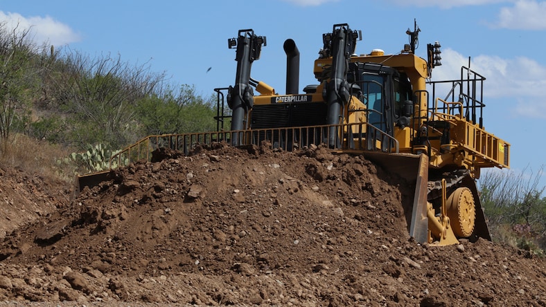 A driverless construction vehicle pushes dirt on a project site.