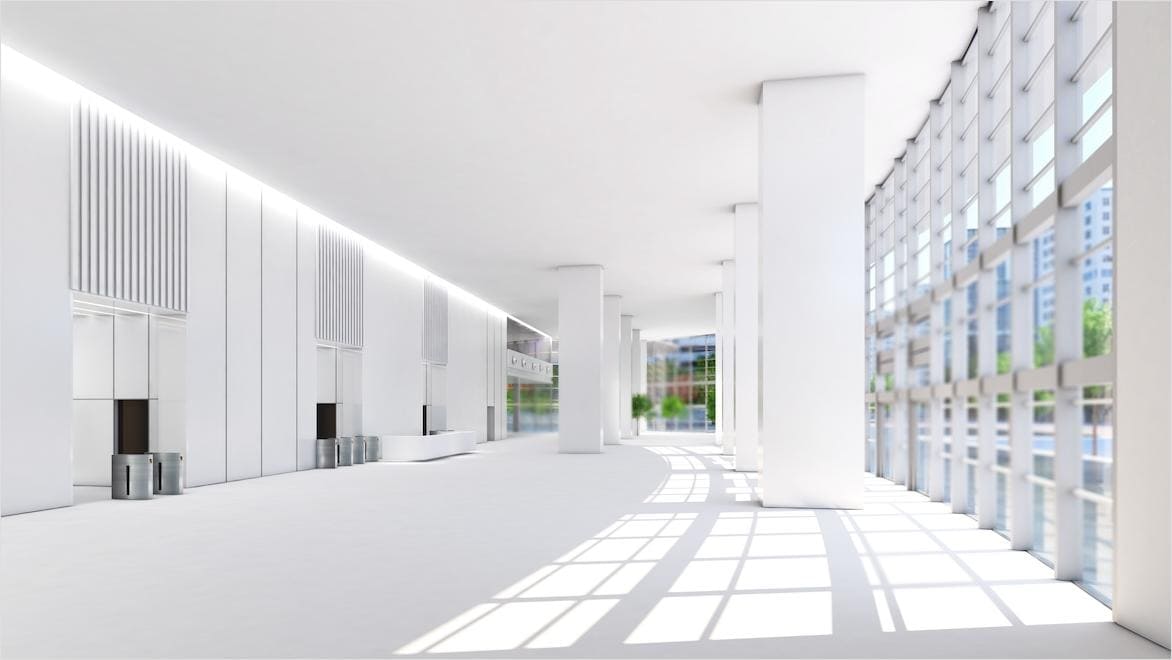 A modern building’s interior is bordered by windows on one wall and artificial lighting on the other.