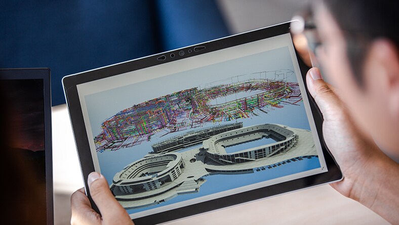 Hands holding a tablet displaying structural designs for the Phoenix Mountain Sports Park