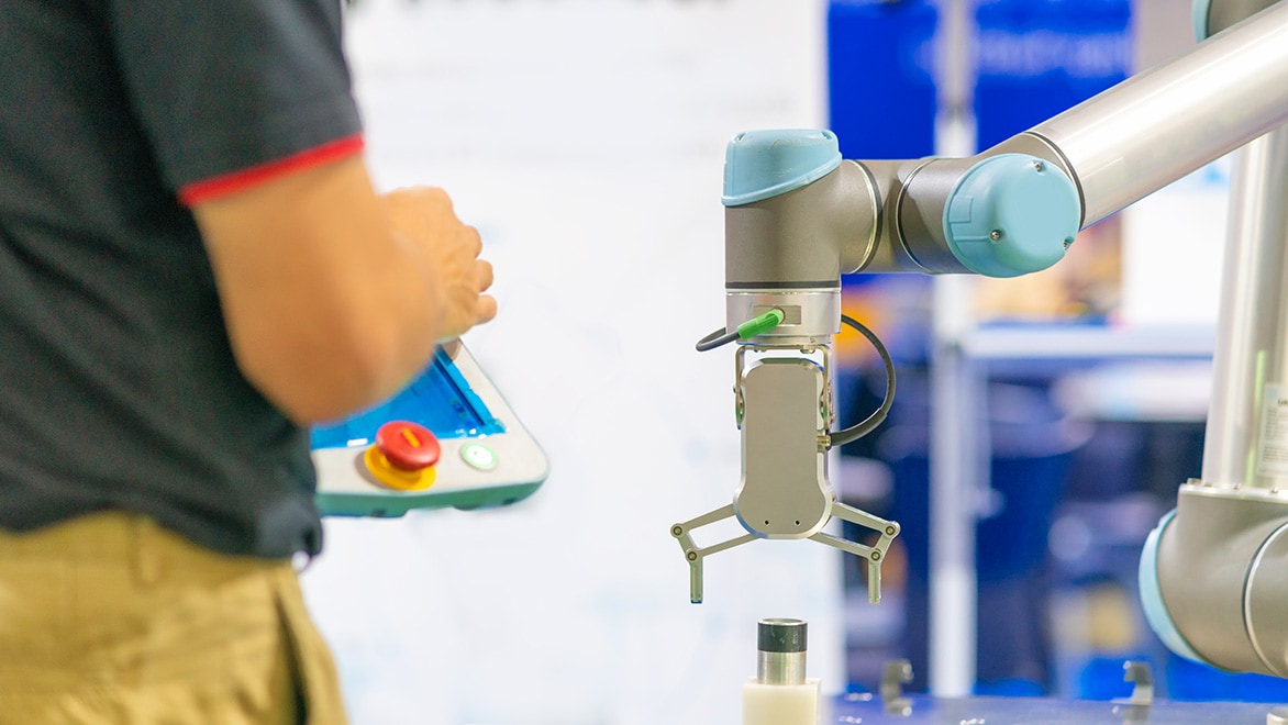 A factory worker operates a robotic arm.