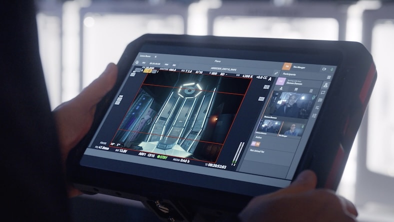A man holds a tablet showing film footage and images of team members as they meet for collaborative review within Flow Capture software.