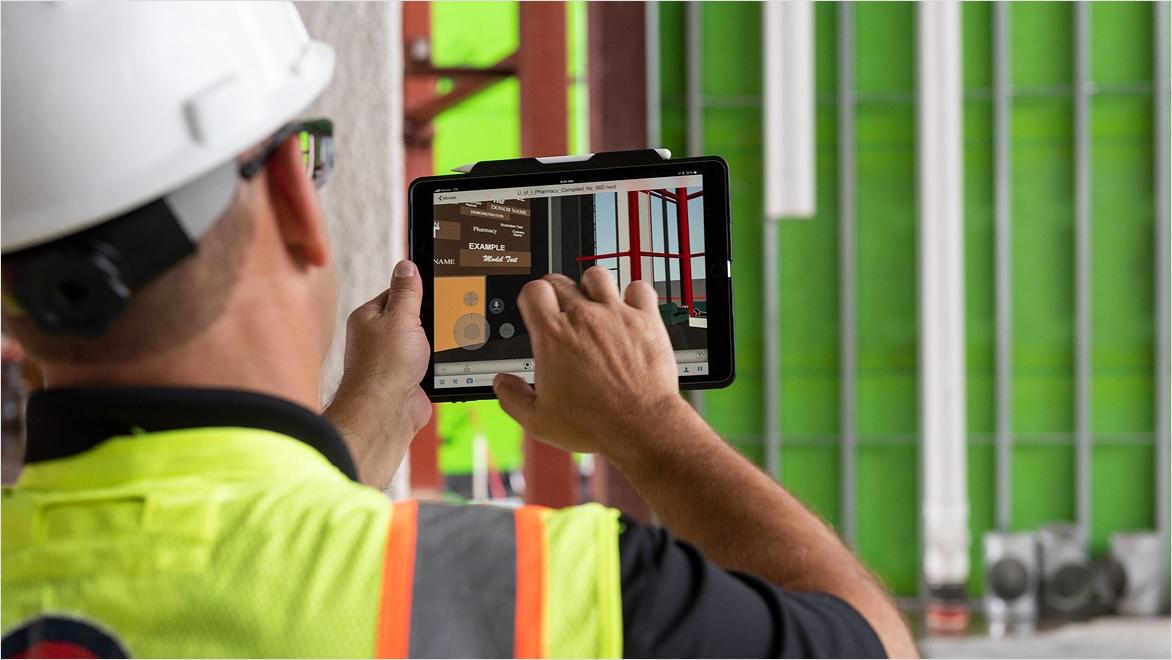 A construction project manager uses a tablet to review blueprints on site.