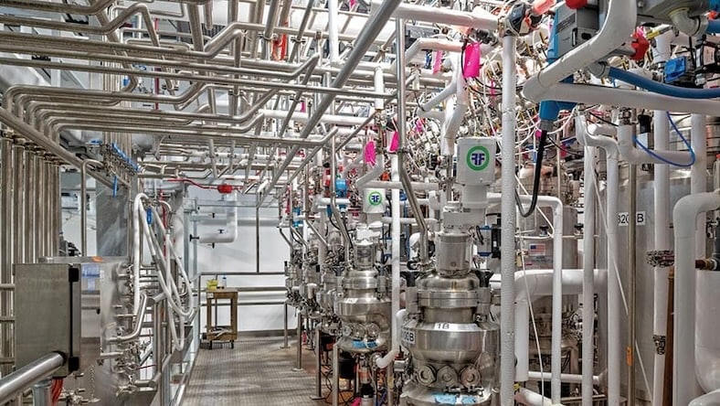 A machine room is filled with shiny metal pipes.