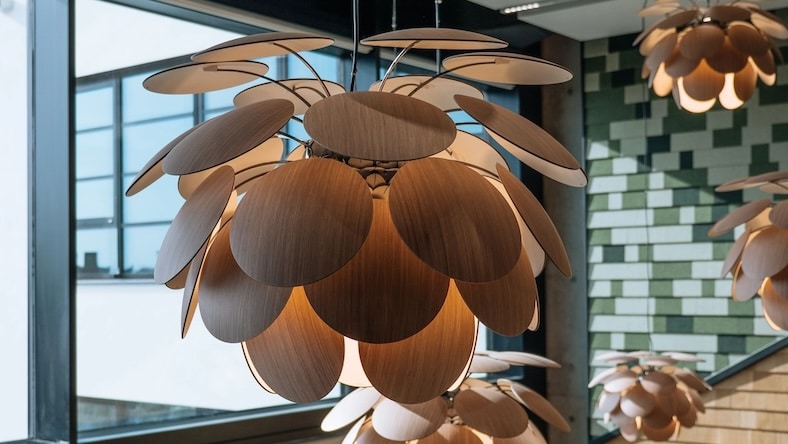 Modern light fixtures with multiple round wooden shades hang from a tall ceiling.