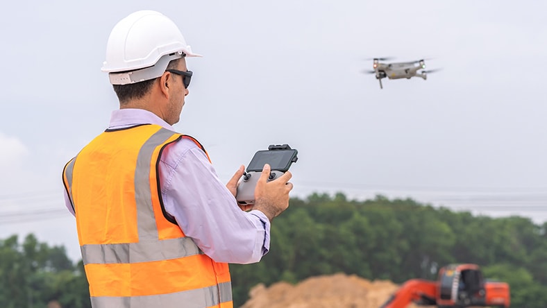 A man surveys a construction site using a drone.