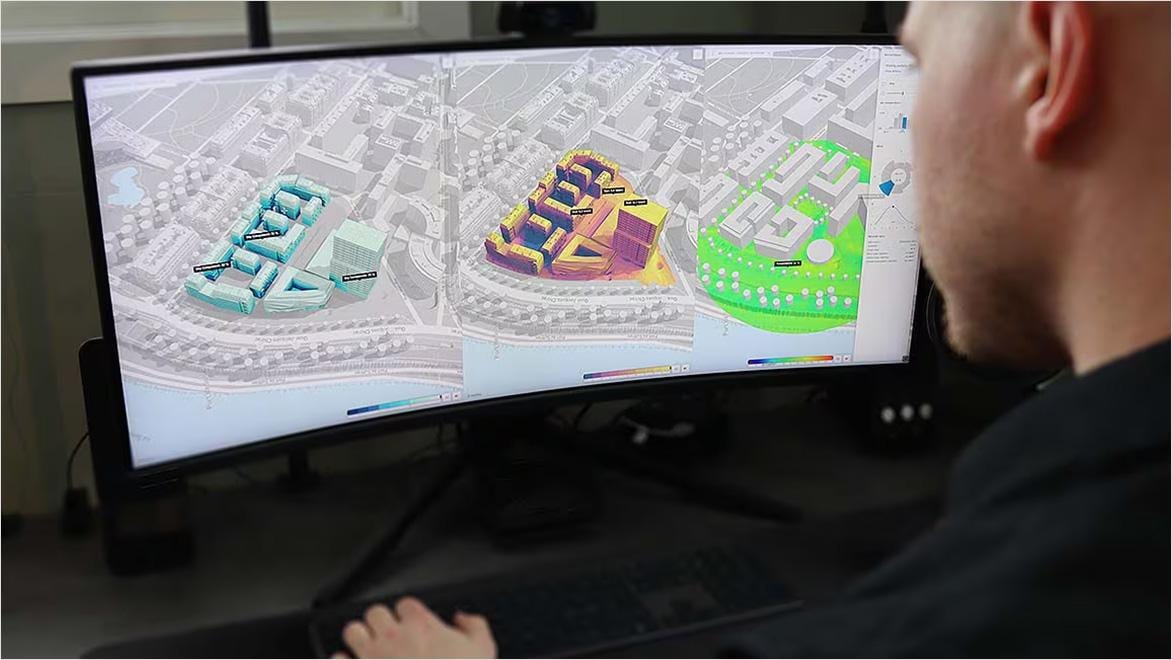 A man looks at a computer screen displaying color-coded building renderings.