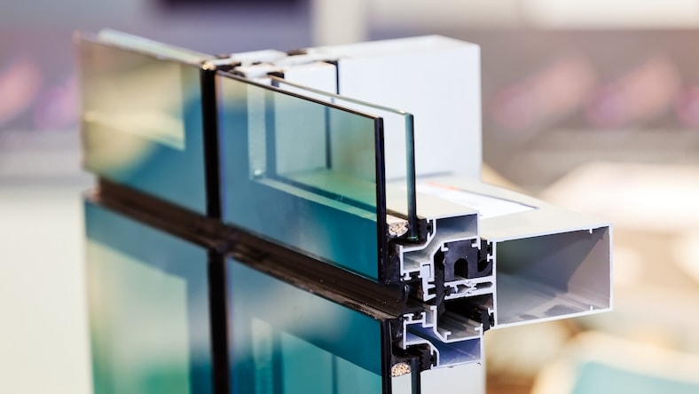 A window panel is cut to show layers of metal, glass, and insulation.