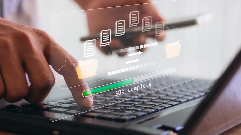 1449917811 A hand using a laptop computer is overlaid with a loading bar icon on a virtual screen.