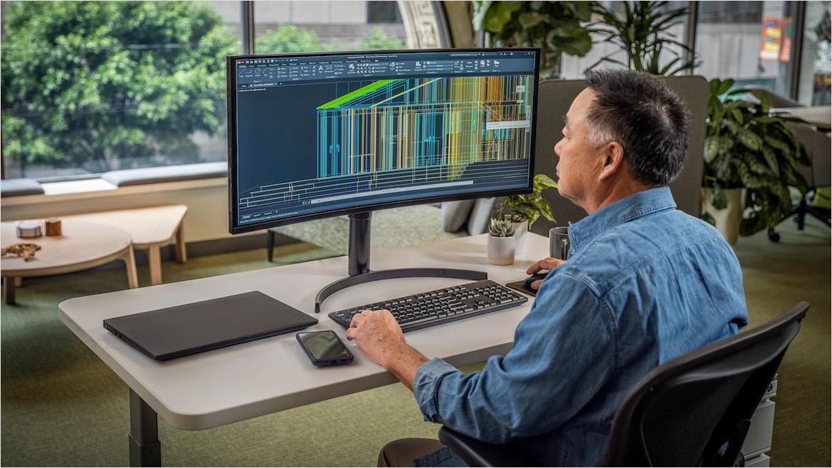 A man sits at a computer working on an architectural diagram.