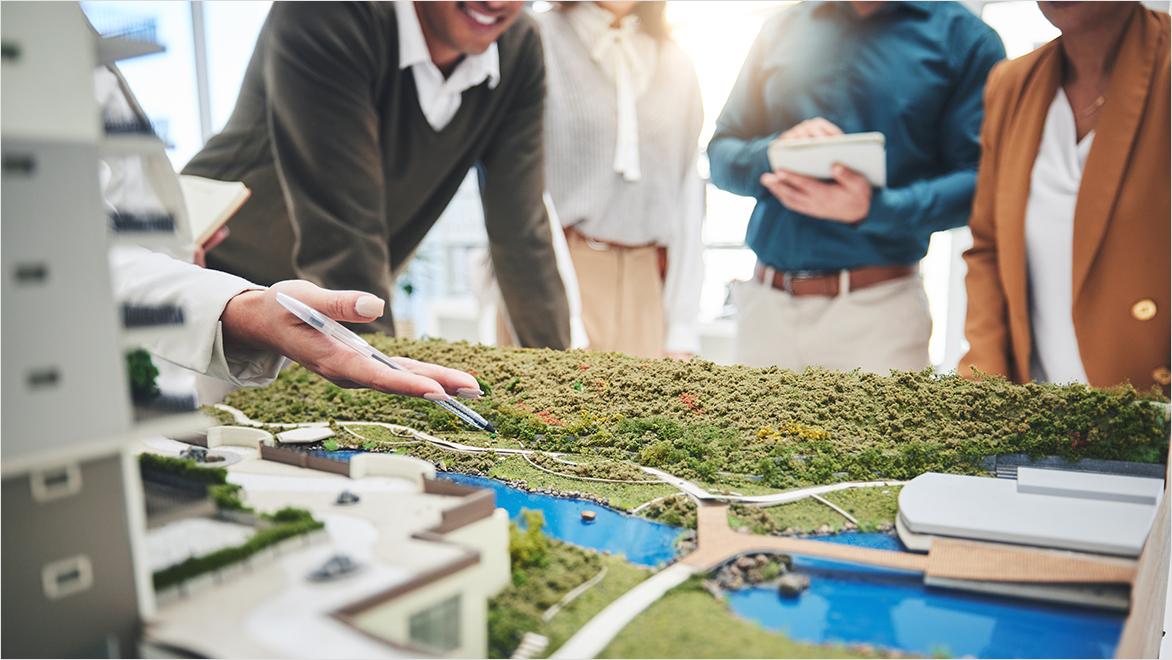 Close-up of people standing around a 3D model of a park and buildings