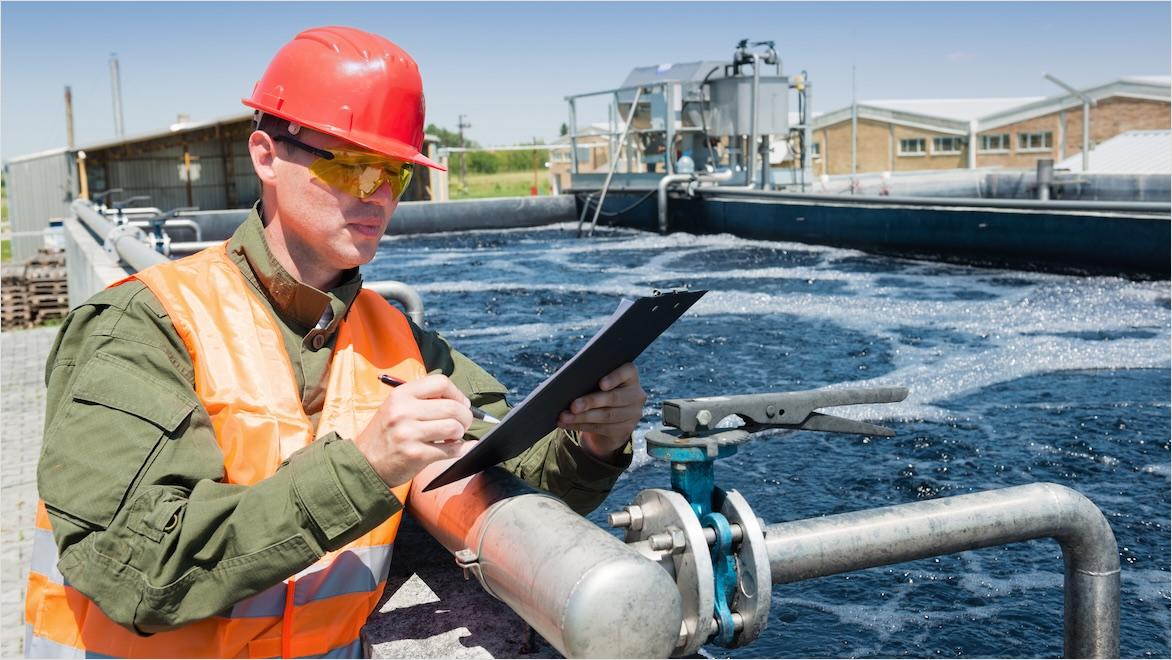 A man in a hard hat inspects a water treatment plant.