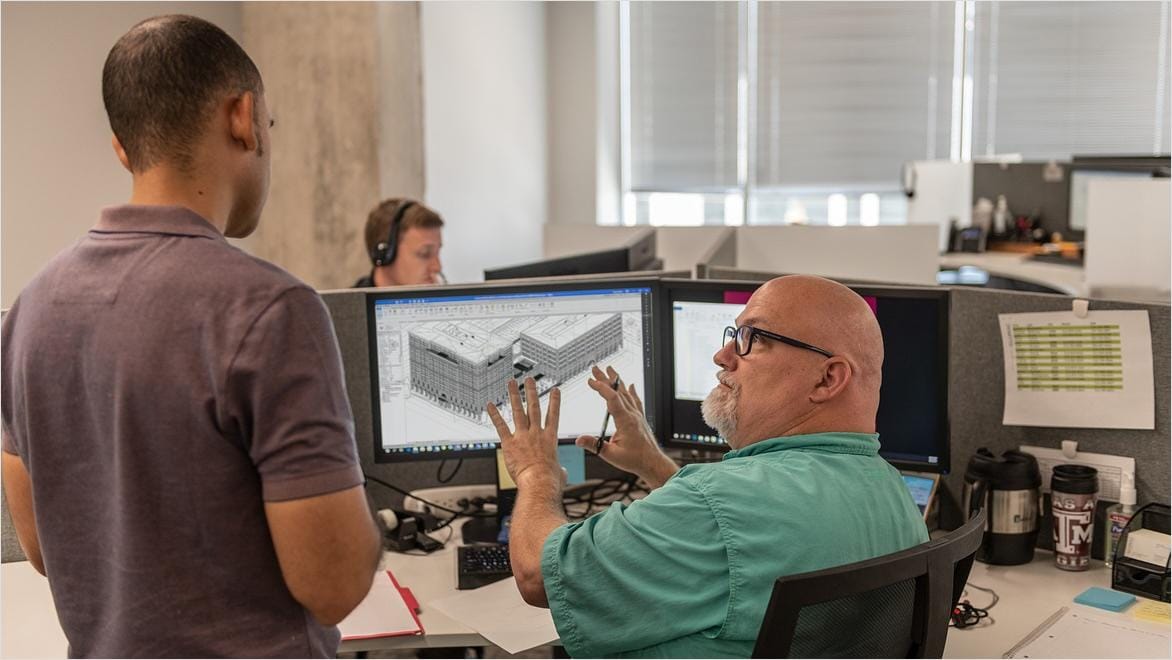Two men in an architectural office discuss the design on a computer monitor