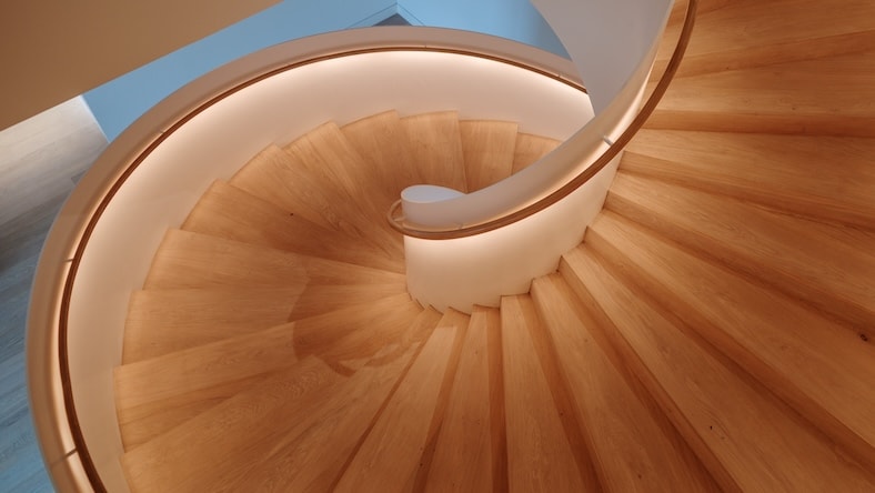 2133930568 An overhead view of a contemporary spiral staircase shows soft indirect lighting directed on the steps from under the railing.