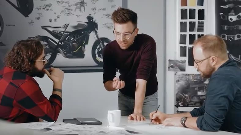 A video still shows 3 Kiska designers at a table reviewing sketches and design ideas for the revived Silverpilen motorcycle.