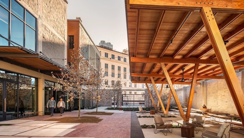 A building courtyard shows modern architectural elements like a wooden roof and oversized windows.