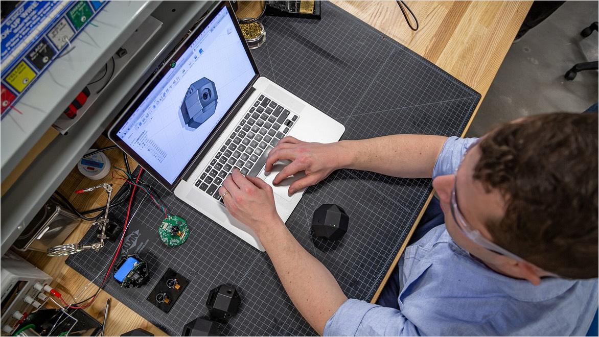 Overhead view of a man working at a laptop displaying Fusion software.