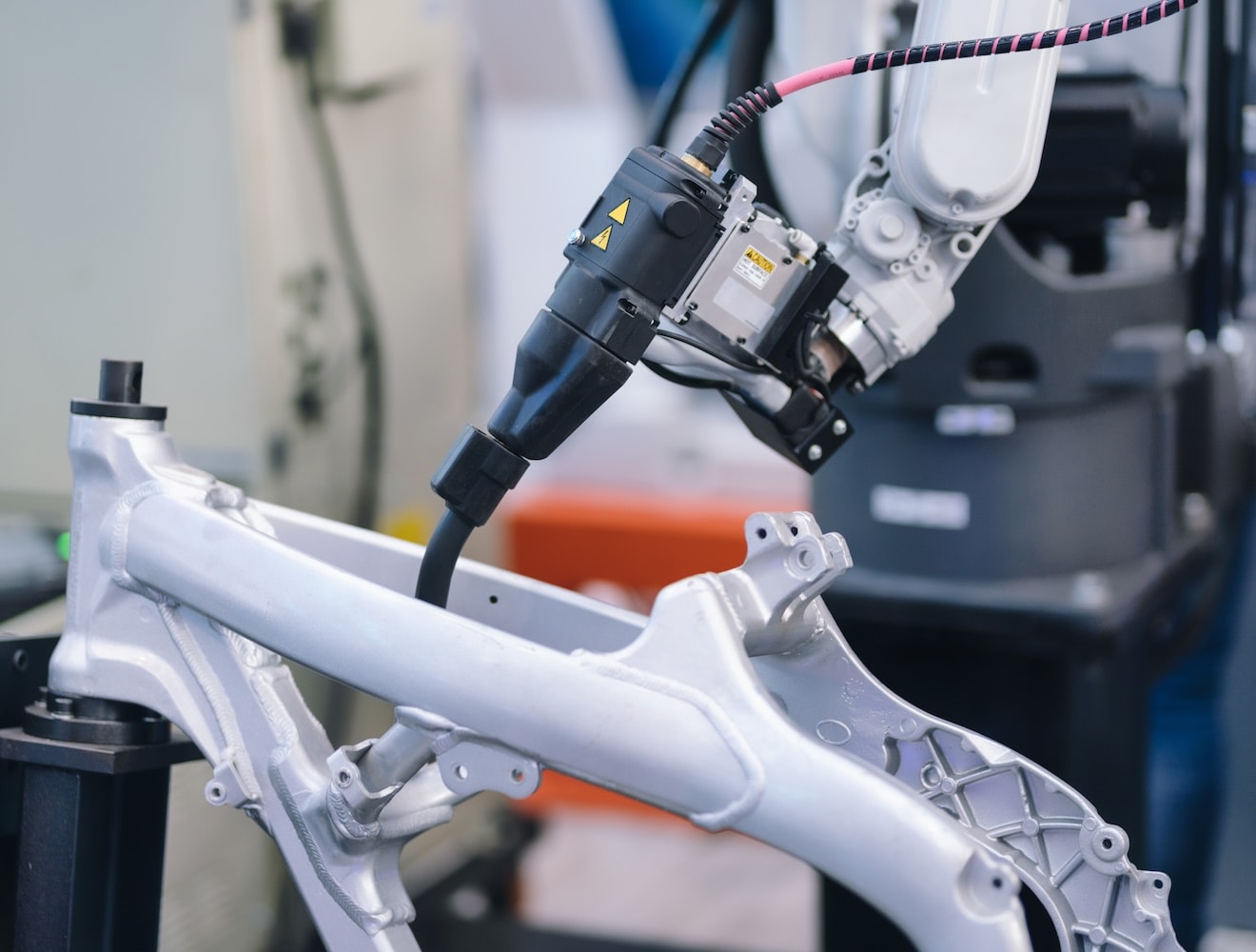 1455438774 Close-up of a robotic arm welding and assembling bicycle parts in a modern factory.