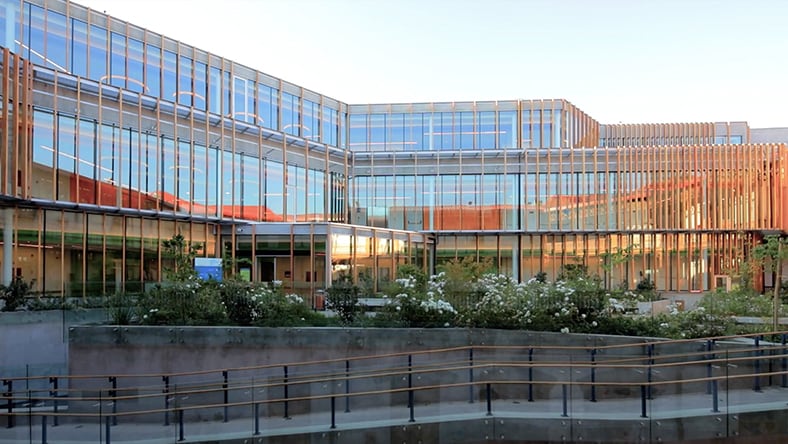 An image shows the outside of the Matta Sur Community Center, a large building with many window panes and an outside garden in Santiago, Chile.