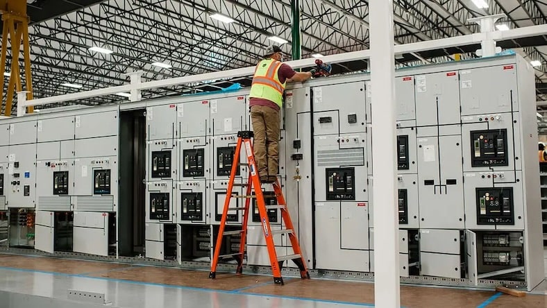 In a factory, a man works on a group of large modules that will be installed in data centers.