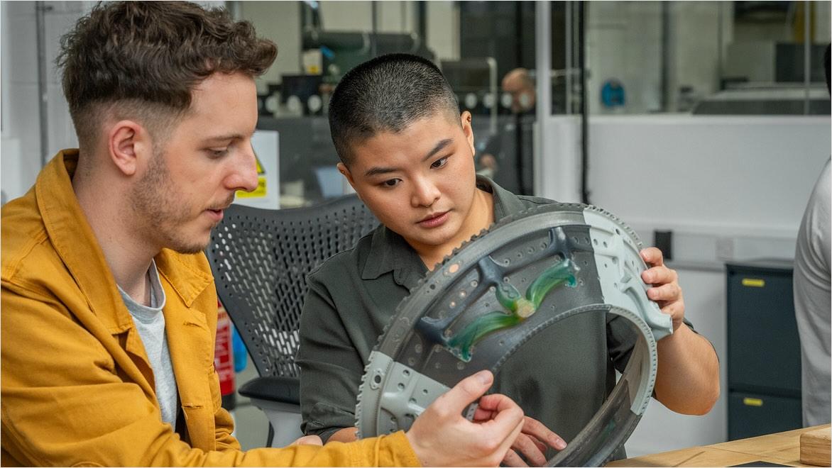 Two people examine a prototype of a machined part.