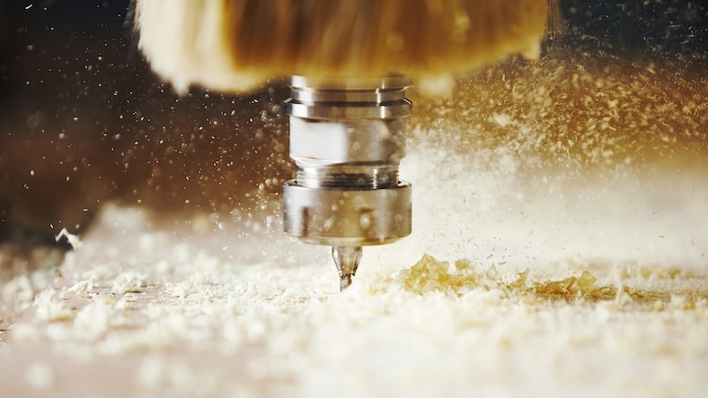 A close-up of a router bit on a CNC machine cutting wood.