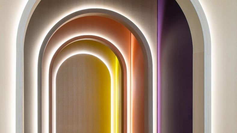 A series of arched doorways is lit by differently colored LED lights.