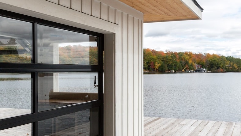 An exterior shot shows the windows, siding, and deck of a lakeside cabin.