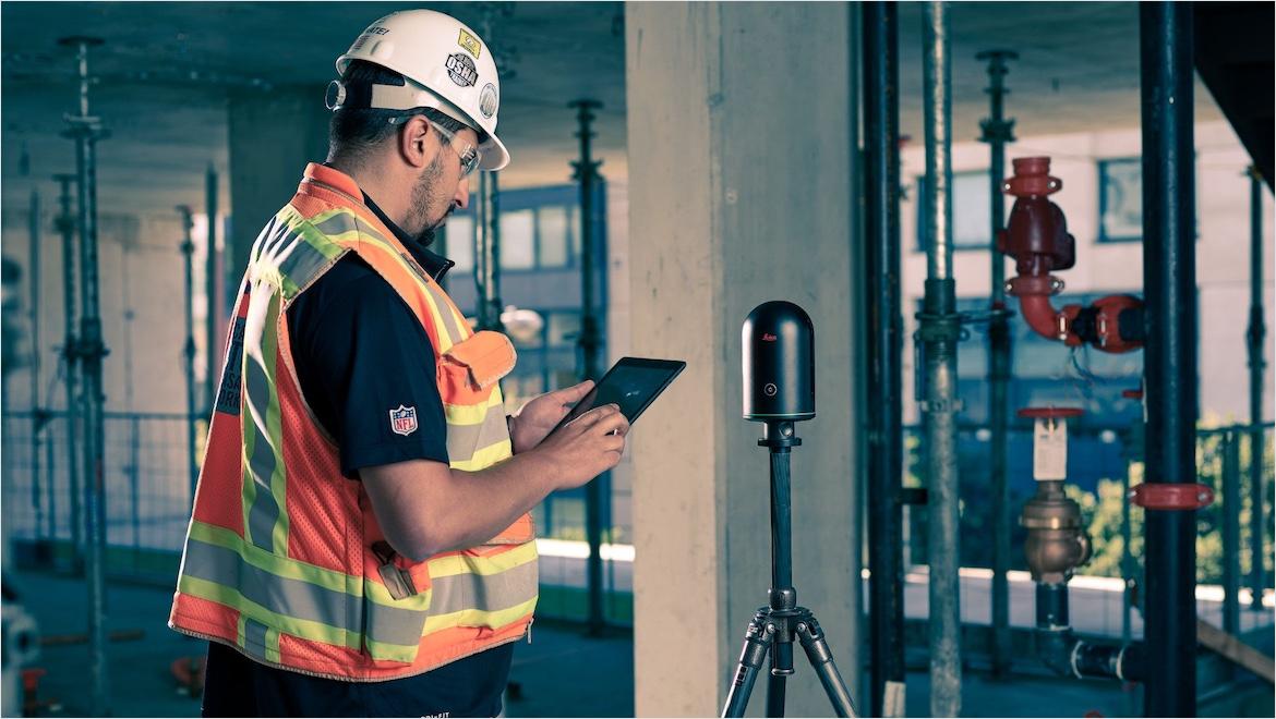 An engineer uses a scanning device to measure a construction site.
