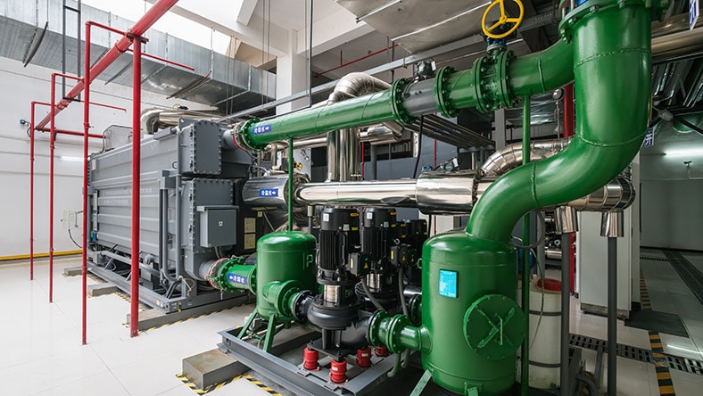 1686953300 Large heat pumps fill a machine room.