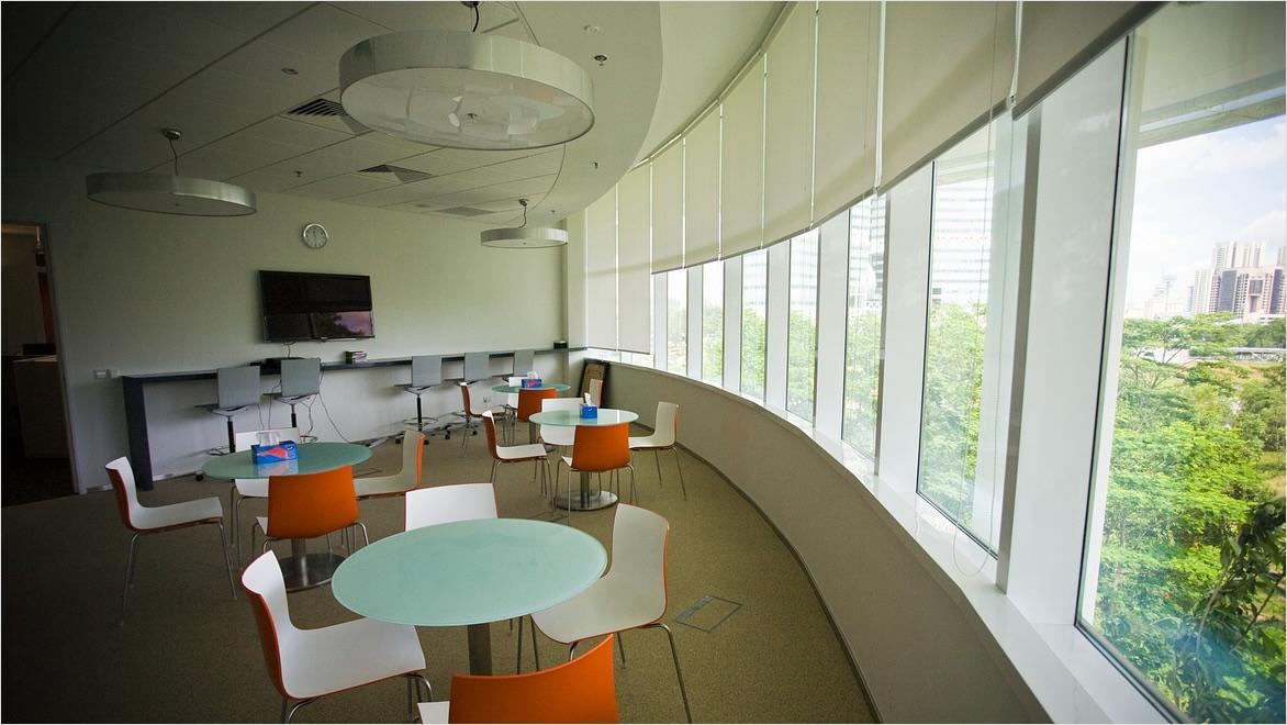 An office space with multiple tables and chairs and a large window in Singapore was created using space design software.