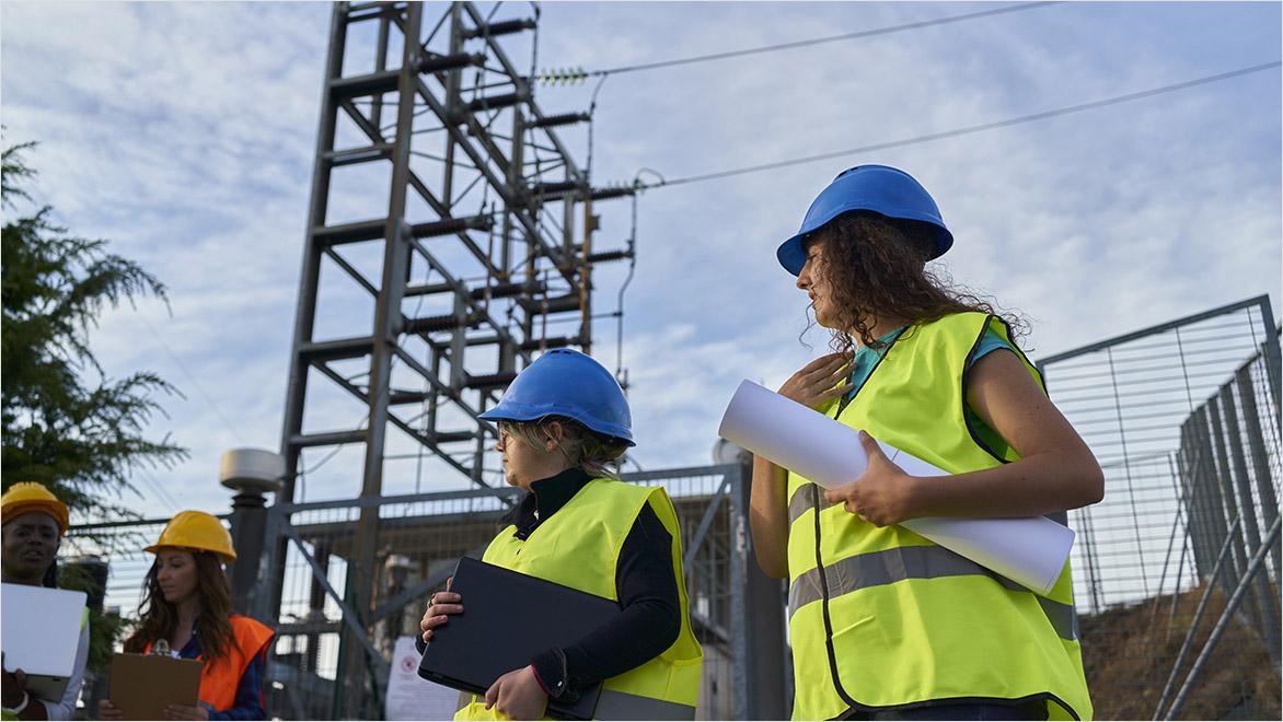 women in construction gear work at a power station.