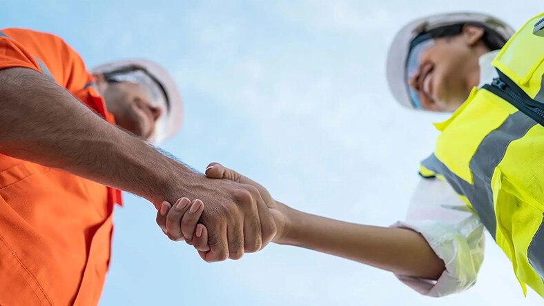 Two construction workers shake hands.