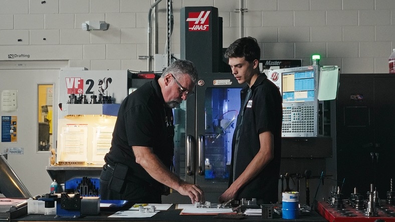 Educator at Suncoast Technical College showing a student a part in a workshop classroom.