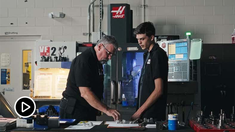 Educator at Suncoast Technical College showing a student a part in a workshop classroom.